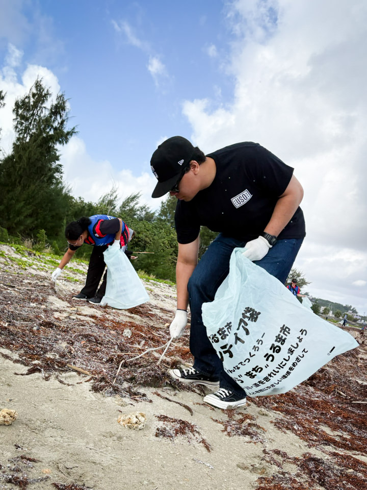 大人の参加者2人が大きなゴミ袋を持って漂着物を回収する様子