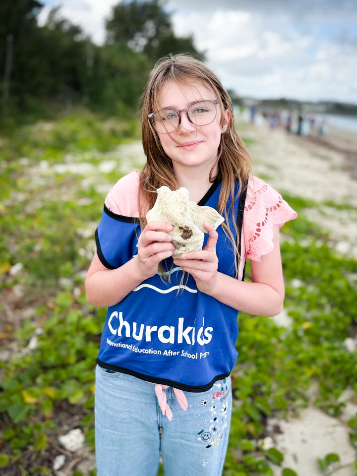 拾った大きな珊瑚石を見せて笑顔の参加者の女の子