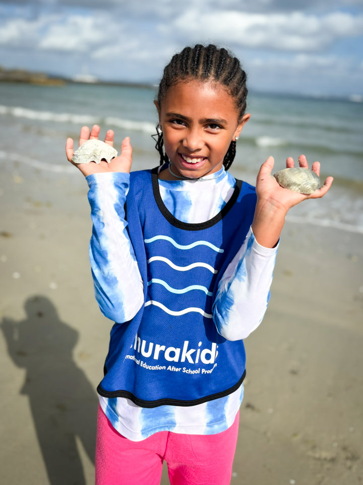 両手いっぱいに集めた貝殻を見せる女の子