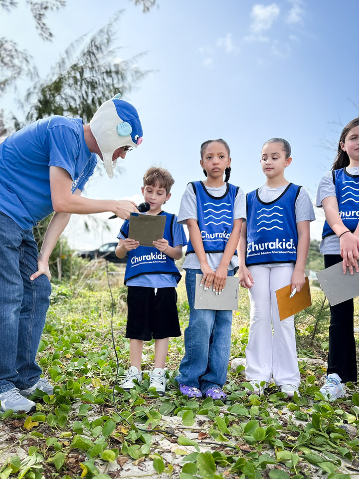 ジャーナルを手に発表を聞く子どもたち
